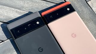 나무 데크 위에 나란히 놓인 Google Pixel 6 Pro(검은색)와 Google Pixel 6(산호색)