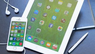 펜과 이어버드가 있는 탁자 위의 iPhone 및 iPad