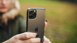 iPhone 사진에서 배경을 흐리게 하는 방법에 대한 기사를 나타내는 iPhone을 들고 사진을 찍는 사람