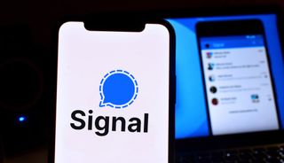 iPhone에 표시되는 Signal 앱 로고와 백그라운드에서 모니터에 표시되는 사용 중인 Signal 앱의 스크린샷.