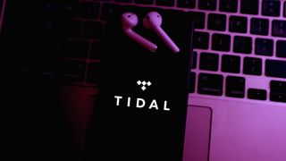 옆에 무선 이어버드가 있는 노트북 키보드에 Tidal 로고가 있는 스마트폰