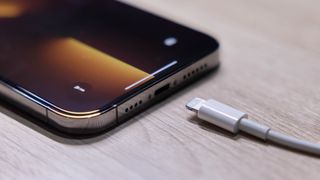 충전 포트 옆에 Lightning 케이블이 있는 테이블 위의 iPhone 13