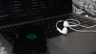 MacBook Air와 Spotify를 실행하는 스마트폰, 키보드에 헤드폰 한 쌍