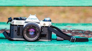 녹색 벤치에 앉아 있는 Canon AE-1 카메라