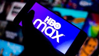 다른 화면 앞에서 어둠 속에서 한 손으로 들고 있는 전화기의 HBO Max 로고