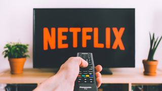 Netflix 로고가 있는 디스플레이를 가리키는 TV 리모컨