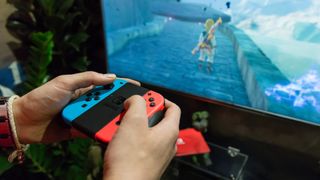 Joy-Con 컨트롤러를 사용하여 TV에서 Breath of the Wild를 플레이하는 Nintendo Switch 플레이어