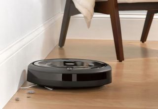 의자를 배경으로 단단한 나무 바닥을 청소하는 irobot roomba e5